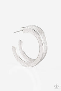 Etched in a scratched shimmer, a flat silver bar curls around the ear, creating a blinding sparkle. Earring attaches to a standard post fitting. Hoop measures 1 1/2” in diameter.  Sold as one pair of hoop earring