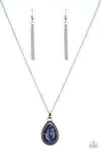 A teardrop blue stone is pressed into a studded silver frame, creating a tranquil pendant below the collar. Features an adjustable clasp closure