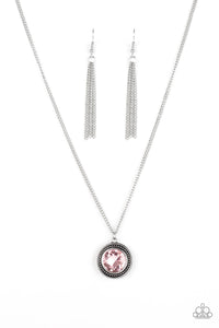 A glittery pink gem is pressed into a studded silver frame, creating a glamorous pendant below the collar. Features an adjustable clasp closure.