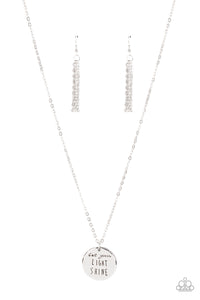 A shiny silver disc is stamped in the inspiring phrase, "Let your light shine," at the bottom of a shiny silver chain. Features an adjustable clasp closure