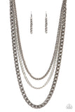 An oversized gunmetal chain, layered with two smaller chains of silver and gunmetal, falls like a weighty medal across the chest creating an edgy industrial effect. Features an adjustable clasp closu