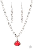 An oversized glassy red gem is pressed into a pronged silver fitting at the bottom of a chunky silver chain, creating a dramatic pendant below the collar. Features an adjustable clasp closure.