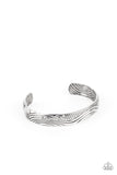 Billowing with wave-like and sections of geometric texture, an embossed silver cuff curls around the wrist for a seasonal look.