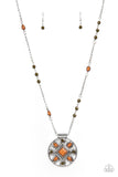 A square brown bead is pressed into the silver studded center of a textured silver hoop radiating with round Olive Branch and teardrop brown beads. The decorative medallion swings from the bottom of a beaded silver chain, creating a colorful tribal inspired display. Features an adjustable clasp cl