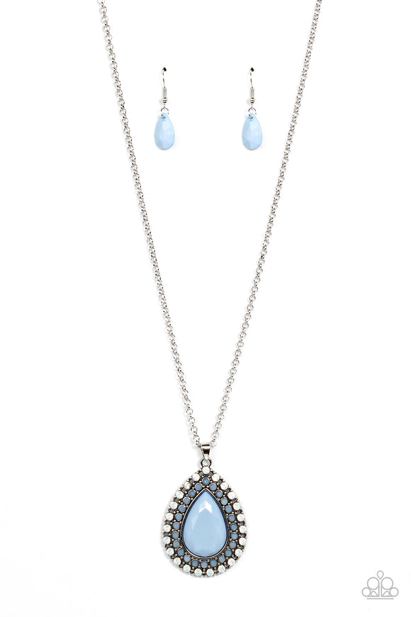 A faceted blue teardrop is pressed into the center of a silver frame bordered in rows of opalescent white and blue beads, creating an ethereal pendant at the bottom of a classic silver chain. Features an adjustable clasp closure.