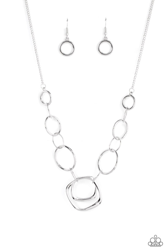 A mismatched collection of silver rings and asymmetrical silver hoops delicately links below the collar, resulting in a modern industrial display. Features an adjustable clasp closure.