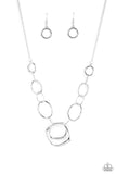 A mismatched collection of silver rings and asymmetrical silver hoops delicately links below the collar, resulting in a modern industrial display. Features an adjustable clasp closure.