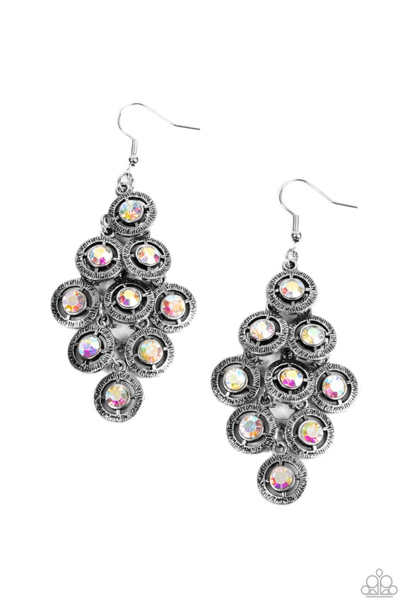 Dotted with iridescent rhinestone centers, tiers of textured silver frames cascade from a metallic backdrop for a stellar tasseled look. Earring attaches to a standard fishhook fitting.