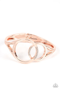 Encrusted in sections of glassy white rhinestones, two oversized rose gold rings delicately overlap across the center of the wrist, resulting in a timeless bangle-like bracelet around the wrist. Features a hinged closure.