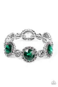 An oversized green rhinestone adorns the center of a hematite rhinestone petaled floral frame. Infused with hematite dotted silver accents, the glitzy floral frames sparkle along stretchy bands around the wrist for a glamorous finis