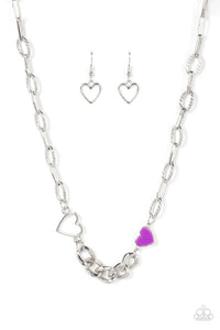 A pair of shiny silver and purple hearts asymmetrically adorn sections of mismatched silver chain, resulting in a flirtatious pop of color below the collar. Features an adjustable clasp closure.