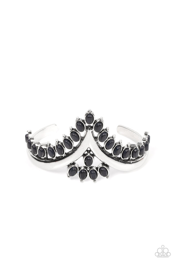 Black oval stones, encased in studded silver frames, line the edge of a daring V-shaped silver cuff. A gathering of black stones adorns the center of the bracelet, adding a finishing touch to the rustically regal cuff