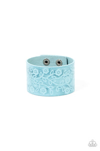 A flowery and leafy motif blooms across the front of a distressed blue leather band, resulting in a rustic floral centerpiece around the wrist. Features an adjustable snap closure.