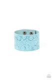 A flowery and leafy motif blooms across the front of a distressed blue leather band, resulting in a rustic floral centerpiece around the wrist. Features an adjustable snap closure.