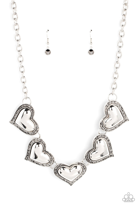 Bordered in glitzy hematite rhinestones, an oversized collection of beveled silver heart frames delicately links below the collar for a dramatically romantic look. Features an adjustable clasp cl