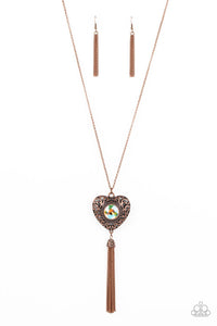 A magical iridescent peach gem sparkles at the center of a 3-dimensional copper heart. Filled with vine-like filigree, the locket-inspired heart pendant glides along an extended copper chain while a shimmery tassel of copper chain dances from the bottom for a flirtatious finish. Features an adjustable clasp closure. Due to its prismatic palette, color may vary.