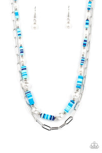 Sections of colorful rubber discs in shades of blue, turquoise, and navy are separated by tiny silver beads and a variety of white baroque pearls to create an unexpected mashup of texture along the collar. A strand of silver paperclip link chain is paired with the abstract design in a layered finish. Features an adjustable clasp closure.