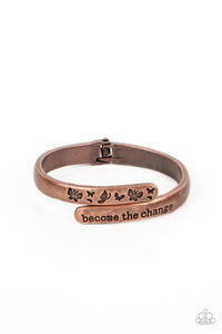 Antiqued copper bars curve and overlap around the wrist, creating a stacked design. One copper bar is stamped with the phrase, "become the change," while the other features engraved butterfly silhouettes in an inspiring finish. Features a hinged closure.