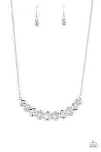 Silver, heart-shaped silhouettes are tilted on their sides, falling in line with variations of the same silver frames encrusted in white rhinestones. The alternating pattern of metallic sheen and glittery shimmer adds eye-catching detail, as the hearts connect into a curved pendant that sits just below the collar. Features an adjustable clasp closure.